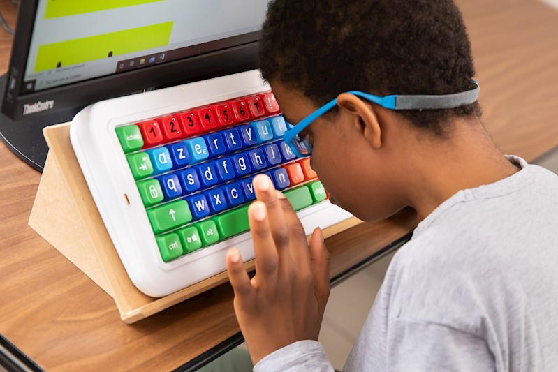Het kind doet oefeningen met behulp van een speciaal toetsenbord voor kinderen met een visuele beperking.